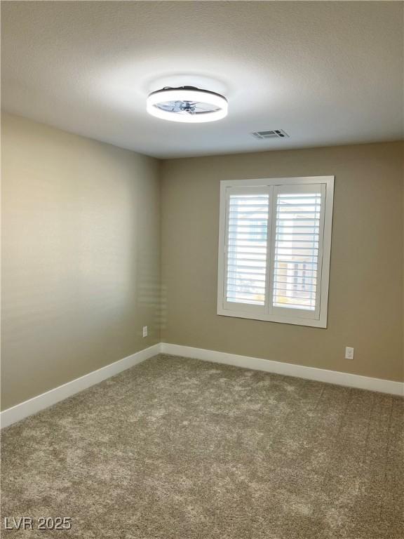 carpeted spare room featuring visible vents and baseboards