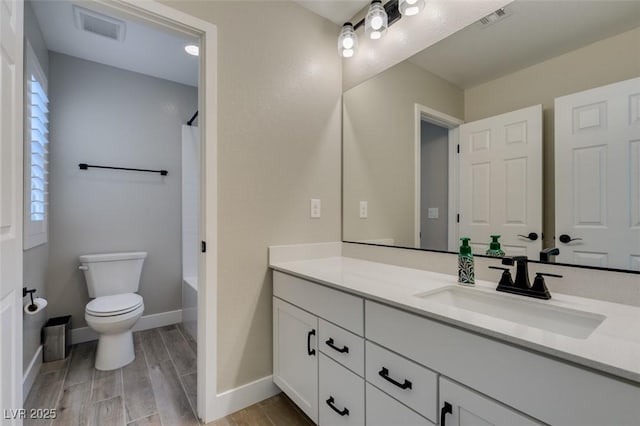 bathroom featuring toilet, vanity, visible vents, and wood finished floors