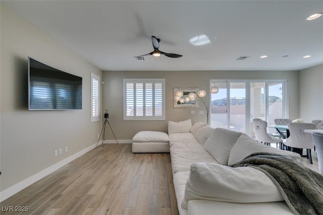 living area featuring light wood-type flooring, visible vents, ceiling fan, and baseboards