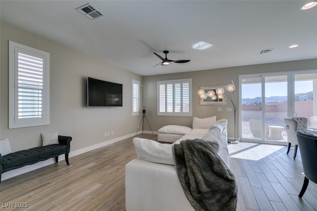living area featuring baseboards, visible vents, ceiling fan, and light wood-style flooring