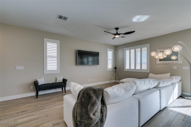 living room with visible vents, ceiling fan, light wood-style flooring, and baseboards