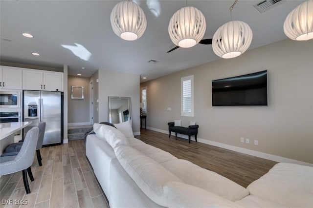 living area with visible vents, recessed lighting, light wood-style flooring, and baseboards