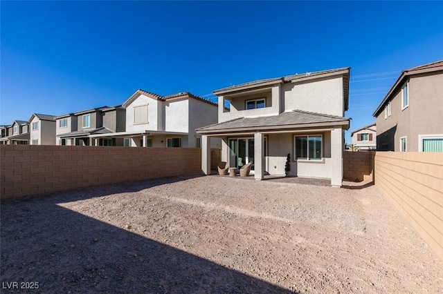 rear view of house with stucco siding, a patio, a residential view, and a fenced backyard