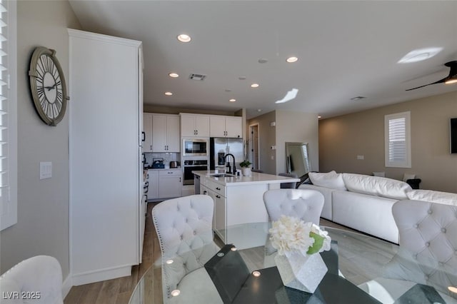 dining space featuring baseboards, visible vents, light wood finished floors, and recessed lighting