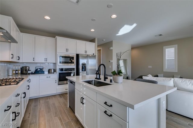 kitchen with a sink, decorative backsplash, light wood-style floors, light countertops, and appliances with stainless steel finishes