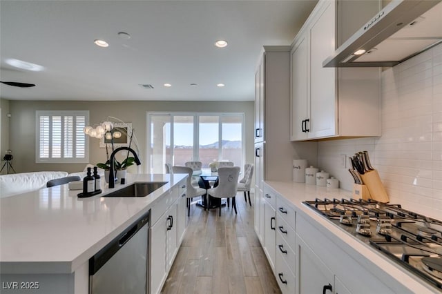 kitchen with recessed lighting, stainless steel appliances, under cabinet range hood, light countertops, and a sink