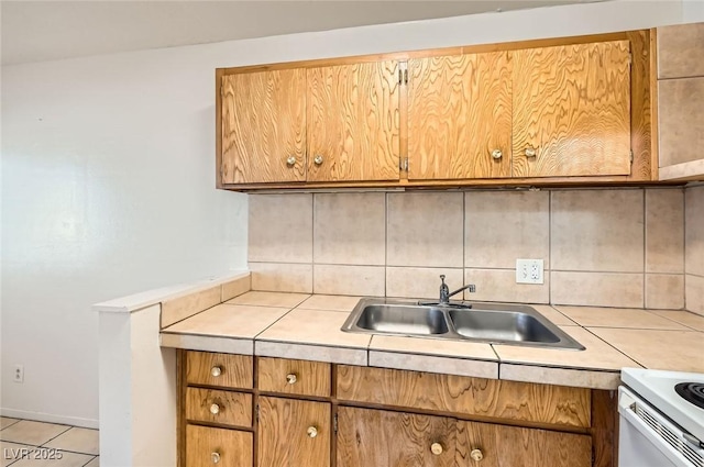 kitchen featuring a sink, tasteful backsplash, brown cabinetry, and light countertops