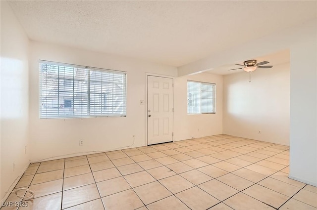 unfurnished room with light tile patterned floors, a ceiling fan, and a textured ceiling