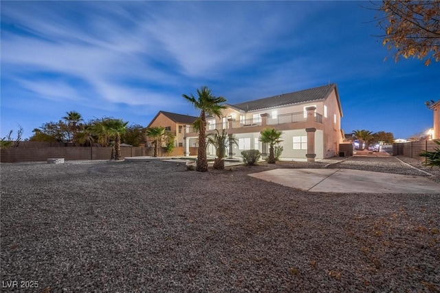 rear view of property featuring fence, a balcony, and stucco siding