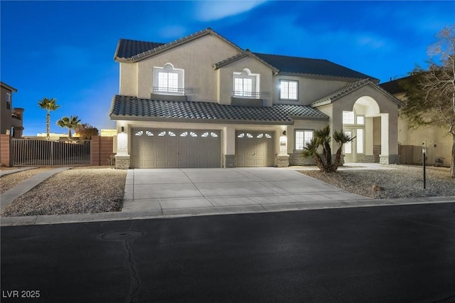 mediterranean / spanish-style house with stone siding, stucco siding, a tiled roof, an attached garage, and driveway