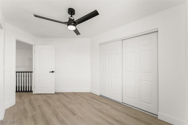 unfurnished bedroom with a ceiling fan, baseboards, light wood finished floors, and a closet