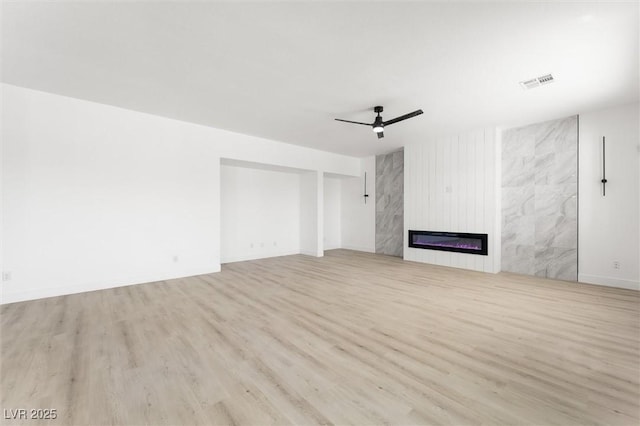 unfurnished living room with ceiling fan, a fireplace, wood finished floors, and visible vents