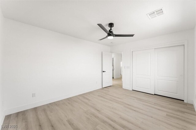 unfurnished bedroom with ceiling fan, visible vents, light wood-type flooring, baseboards, and a closet