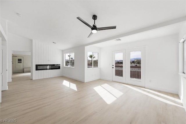 unfurnished living room featuring ceiling fan, visible vents, a fireplace, baseboards, and light wood finished floors