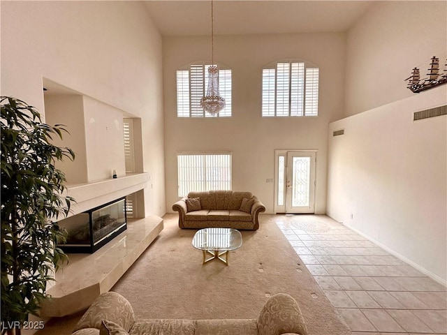 tiled living area featuring a high ceiling, a tile fireplace, and a chandelier