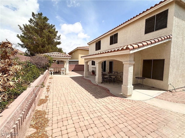 back of property with stucco siding, a patio, a fenced backyard, and a tile roof
