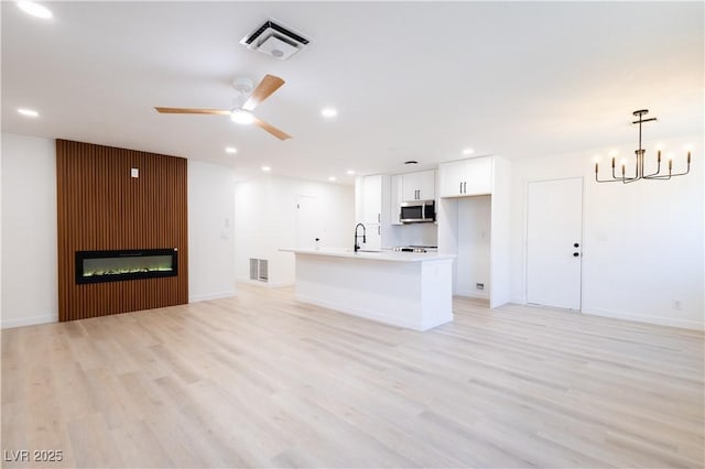 unfurnished living room featuring visible vents, recessed lighting, light wood finished floors, and a sink