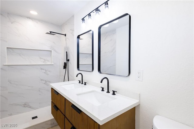 full bathroom featuring double vanity, toilet, a marble finish shower, and a sink