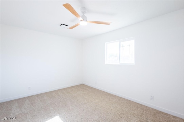 carpeted spare room with baseboards, visible vents, and a ceiling fan