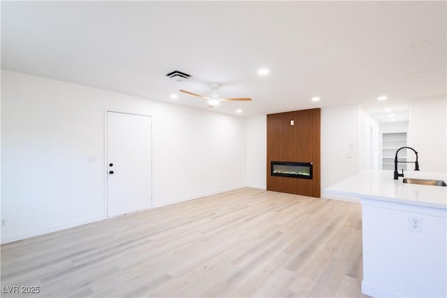 interior space featuring recessed lighting, a large fireplace, a sink, ceiling fan, and visible vents