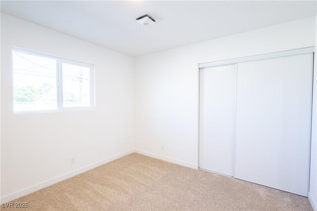 unfurnished bedroom with baseboards, visible vents, carpet floors, and a closet