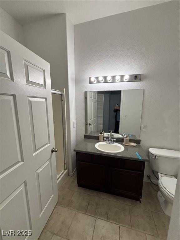 bathroom featuring toilet, a stall shower, tile patterned flooring, and vanity