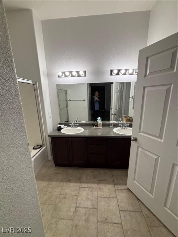 full bath featuring a bath, a shower with door, double vanity, and a sink