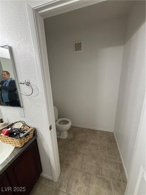 bathroom with baseboards, visible vents, toilet, and vanity