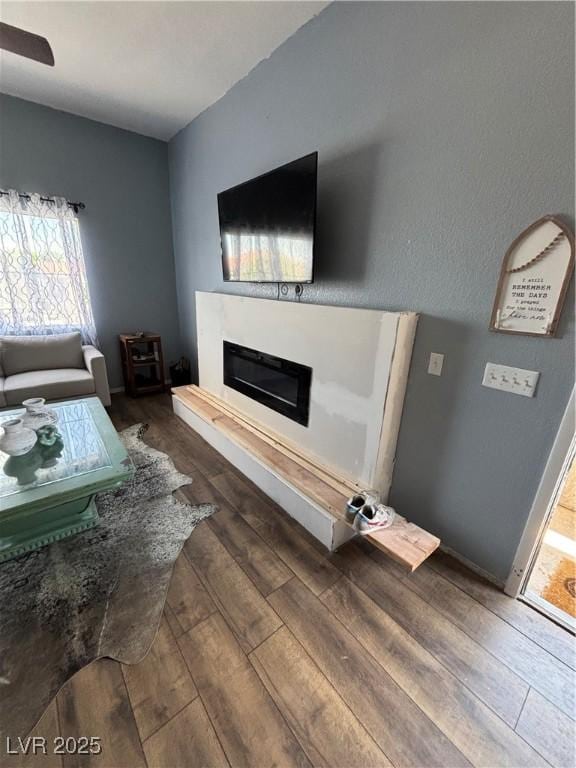 living area with a wealth of natural light, wood finished floors, and a glass covered fireplace