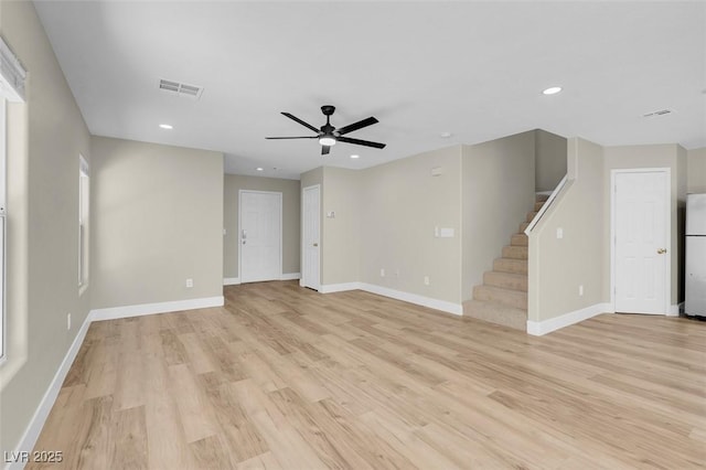 unfurnished living room featuring light wood finished floors, stairway, a ceiling fan, visible vents, and baseboards
