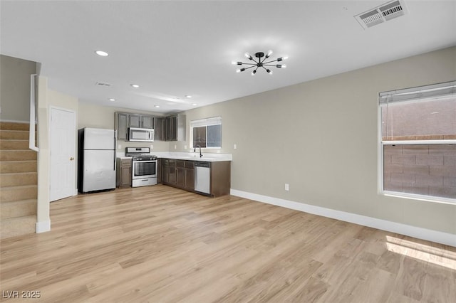 kitchen with stainless steel appliances, light wood-style floors, visible vents, baseboards, and light countertops