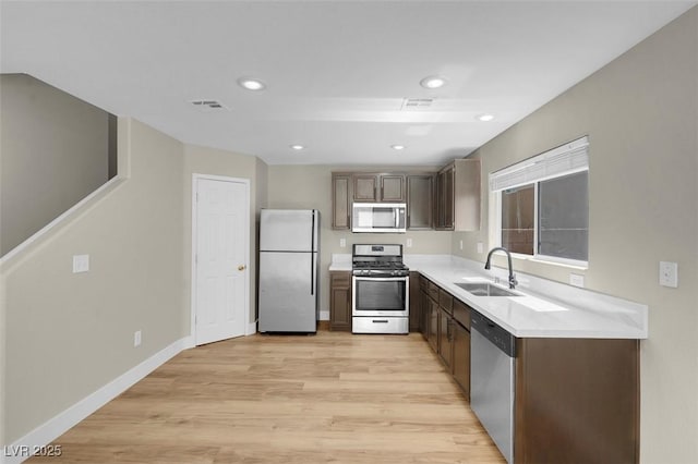 kitchen featuring light wood-style flooring, stainless steel appliances, light countertops, a sink, and visible vents