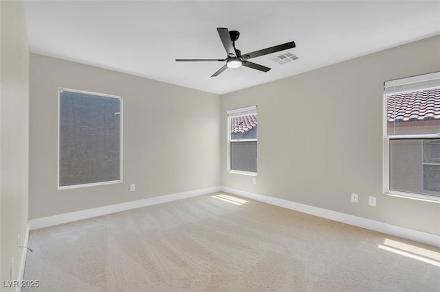carpeted spare room with baseboards, visible vents, and a ceiling fan