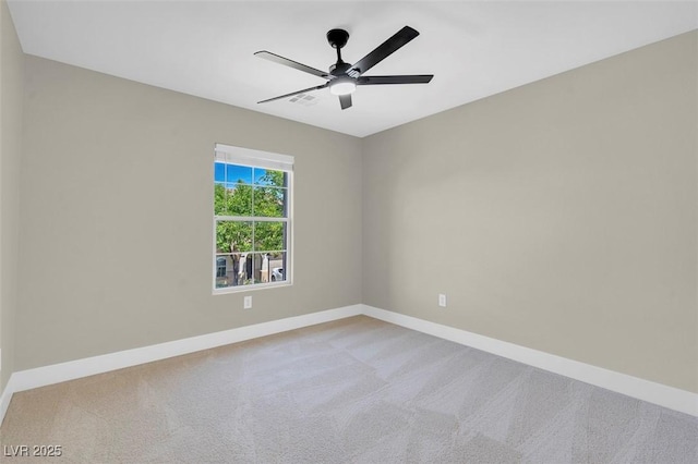 empty room with baseboards, visible vents, ceiling fan, and light colored carpet