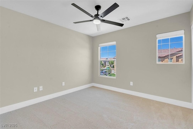 carpeted spare room featuring visible vents, a ceiling fan, and baseboards