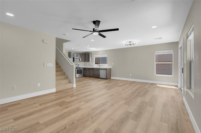 unfurnished living room featuring stairway, light wood-style floors, baseboards, recessed lighting, and a ceiling fan
