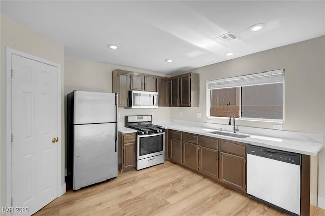 kitchen featuring a sink, appliances with stainless steel finishes, light wood-style floors, visible vents, and light countertops