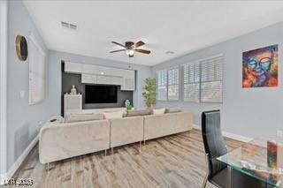 living area with a ceiling fan, baseboards, visible vents, and wood finished floors