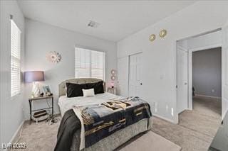 bedroom with baseboards, multiple windows, a closet, and light colored carpet