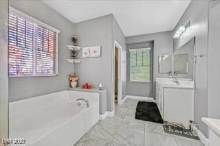 full bath with vanity, baseboards, a bath, and marble finish floor