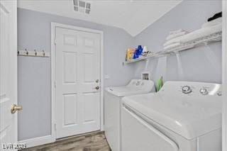 clothes washing area featuring laundry area, wood finished floors, and washing machine and clothes dryer
