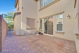 back of property with fence, stucco siding, and a patio area