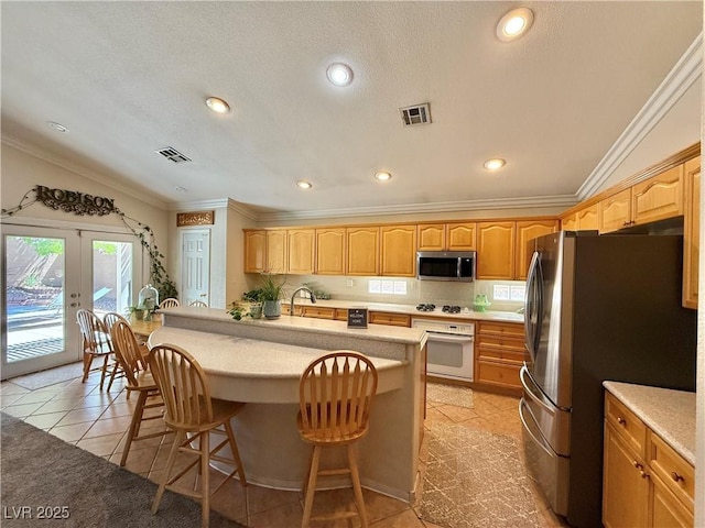 2986 Matese Dr, Henderson, NV 89052 - kitchen with visible vents, crown molding, appliances with stainless steel finishes, and a breakfast bar