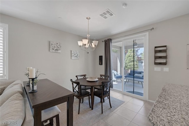 dining area with light tile patterned flooring, visible vents, a chandelier, and baseboards