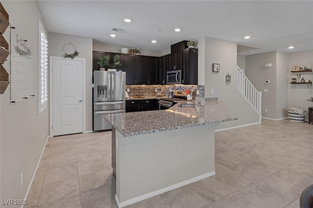 kitchen with a sink, visible vents, stainless steel appliances, light stone countertops, and a peninsula