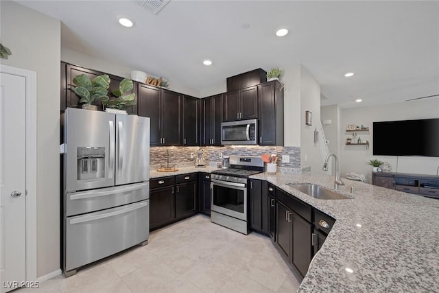 kitchen featuring light stone counters, decorative backsplash, stainless steel appliances, a sink, and visible vents