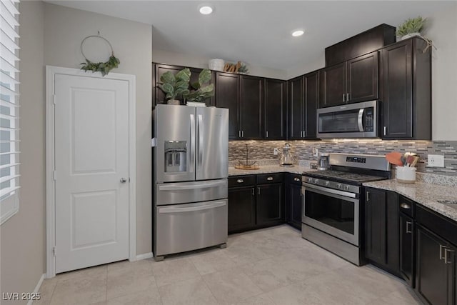 kitchen with light stone counters, stainless steel appliances, baseboards, light tile patterned flooring, and backsplash