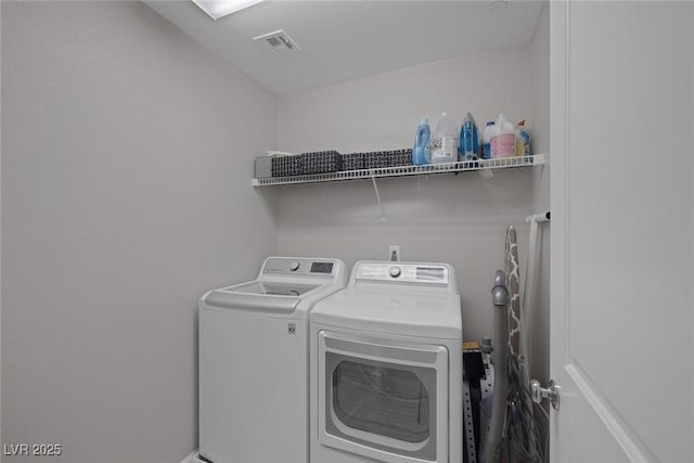 clothes washing area featuring visible vents, washer and dryer, and laundry area