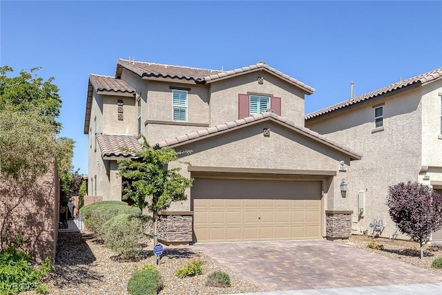 view of front facade with stucco siding, a tile roof, decorative driveway, and stone siding