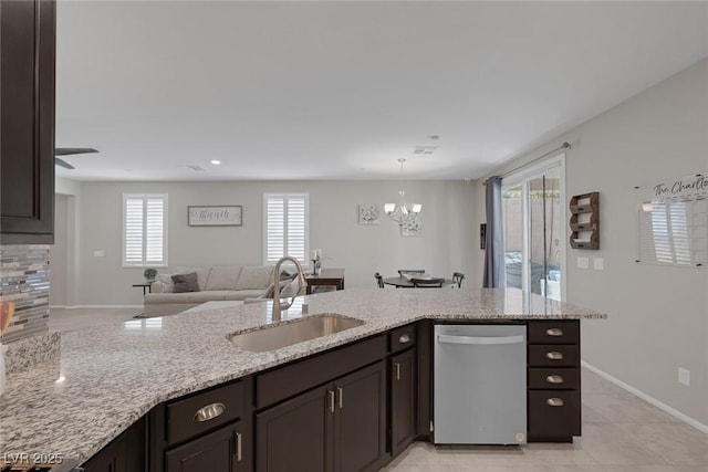 kitchen with light stone countertops, a chandelier, stainless steel dishwasher, and a sink
